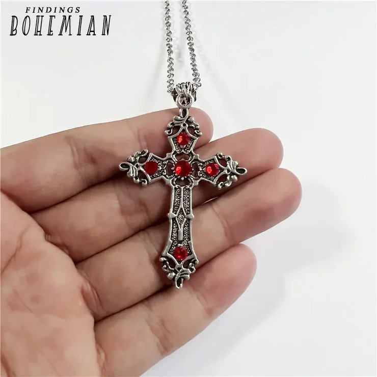 Intricate Christian Silver Pendant Jewelry cross with red gemstone accents held in hand