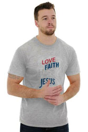 Man wearing a grey Christian graphic t-shirt with words Love Faith Jesus printed in red and blue