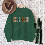 Green crewneck sweatshirt with God is Good print styled as Christian clothing women with brown hat and cactus