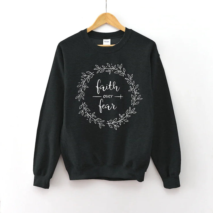 Black Christian women's sweatshirt with faith over fear script and decorative wreath design