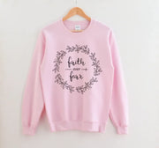 Pink Christian women's sweatshirt with faith over fear floral wreath design hanging on wooden hanger
