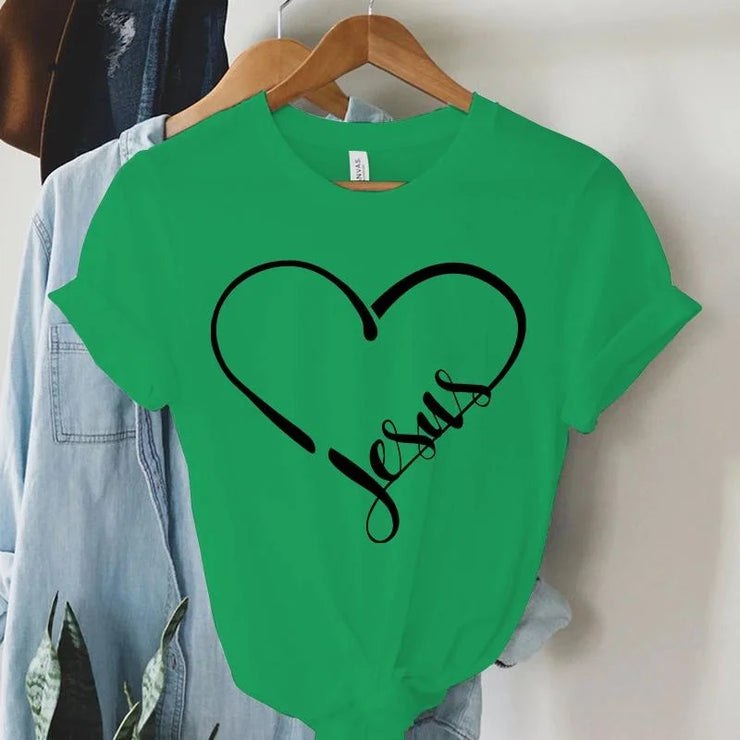 Green Christian women's t-shirt with black heart and Jesus text design hanging on wooden hanger