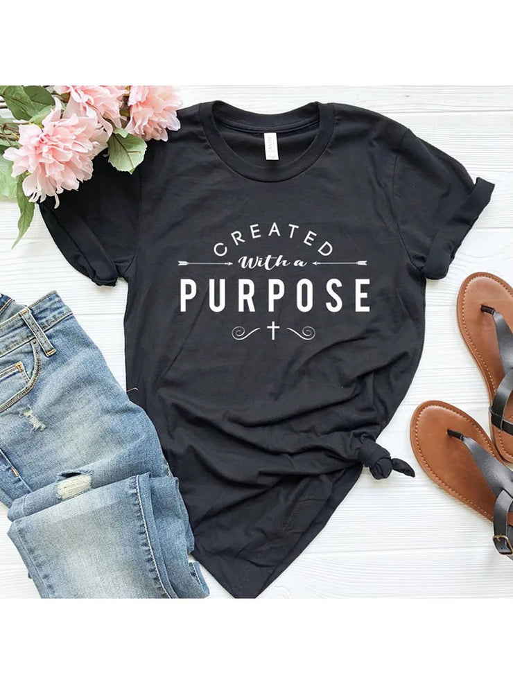 Black Created with a Purpose shirt featuring white typography and cross design styled with jeans and sandals