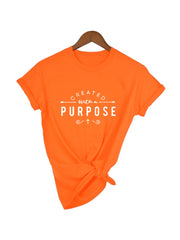 Bright orange Created with a Purpose shirt by Fresh Faith Designs with white inspirational text and cross graphic