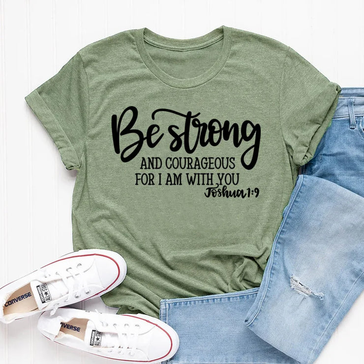 Olive green faith based apparel t-shirt with Be strong and courageous Joshua 1 9 text paired with light blue jeans and white Converse shoes