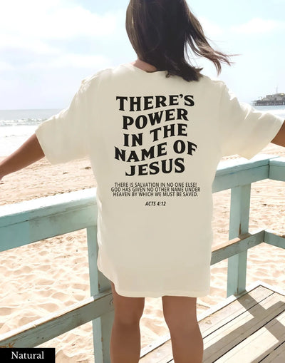 Woman wearing faith based women's apparel white shirt with there's power in the name of Jesus text at the beach