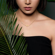 Minimalist gold cross necklace on woman wearing black strapless top faith jewelry for women