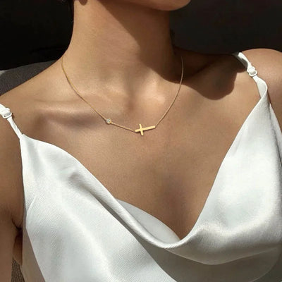 Delicate gold cross necklace on woman wearing a white satin top faith jewelry for women