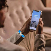Fresh Faith Designs NFC religious jewelry blue bracelet with black cross worn while using smartphone