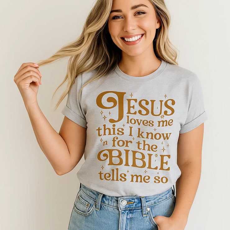 Woman wearing a gray Jesus Loves Me T-Shirt with golden Bible quote from Fresh Faith Designs