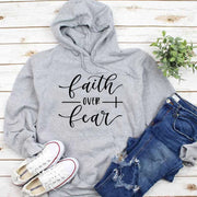 Gray hoodie with faith over fear text paired with ripped jeans and white sneakers religious casual apparel