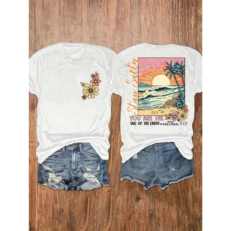 Fresh Faith Designs Bible verse beach shirt with floral front and sunset ocean back print paired with denim shorts